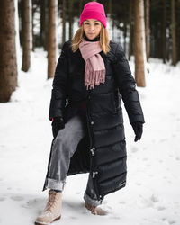 Full length portrait of young woman standing on snow covered land during winter