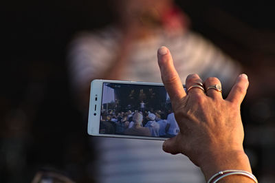 Cropped man photographing with mobile phone during concert