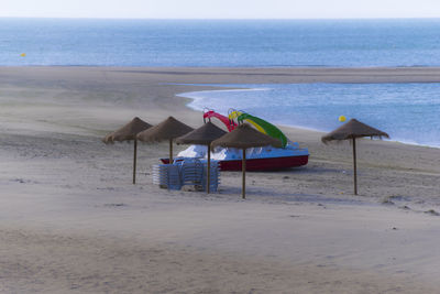 Deck chairs on beach against sky