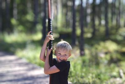 Portrait of boy standing against trees