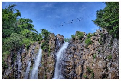 Scenic view of waterfall in forest against sky