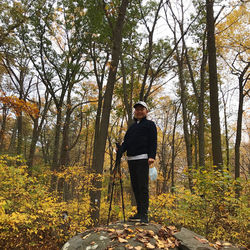 Young man standing by tree in forest