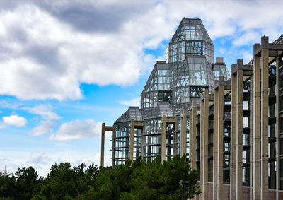 Low angle view of modern building against cloudy sky