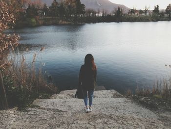 Rear view of woman on lake against sky