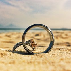 Close-up of wedding rings on sandy beach