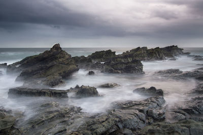 Scenic view of rocks in sea against sky