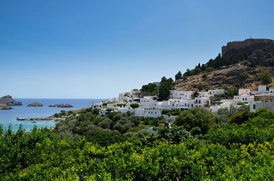 Scenic view of sea and mountains against clear blue sky