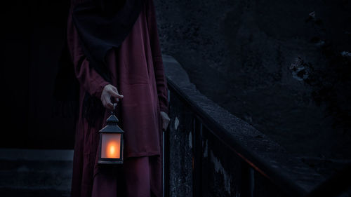 Man standing by illuminated light lantern on building at night