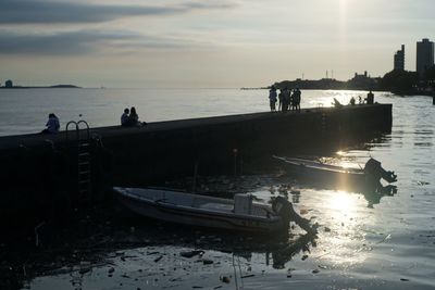 People on beach against sky during sunset