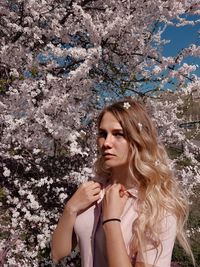Beautiful young woman against white flowering tree