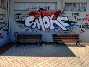 Graffiti on empty bench against wall