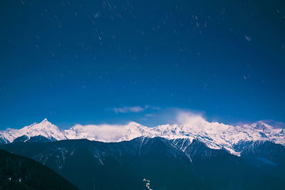 Scenic view of snowcapped mountains against sky at night