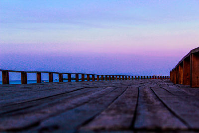 Surface level of pier against sky at sunset