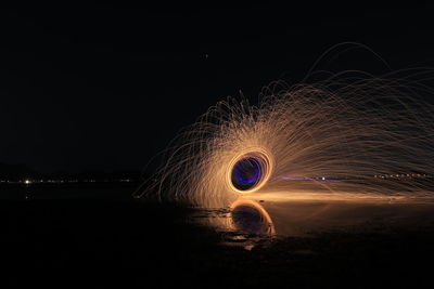 Light trails on beach against sky at night