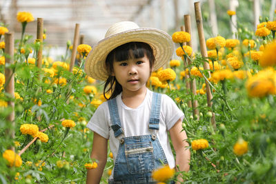 Portrait of young woman standing amidst yellow flowering plants