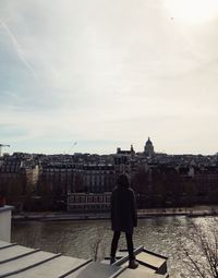 Rear view of man looking at cityscape against sky