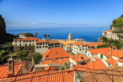 High angle view of townscape by sea against blue sky