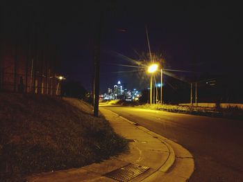 Illuminated road against sky at night