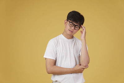 Portrait of teenage girl standing against yellow background