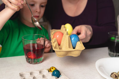 Grandmother helps her grandson paint easter eggs. easter preparation