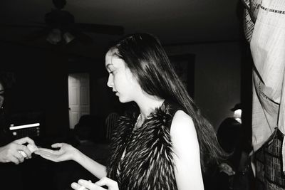 Teenage girl wearing fur jacket standing at home