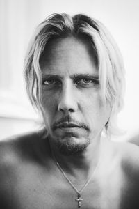 Close-up portrait of shirtless man against wall at home