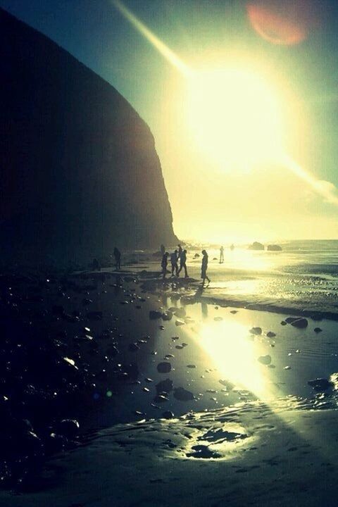 sea, sun, water, lifestyles, leisure activity, silhouette, beach, horizon over water, sunbeam, sunlight, men, sunset, sky, lens flare, shore, full length, walking, reflection