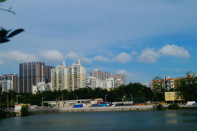 Buildings by river against sky in city