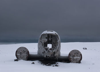 Abandoned building by sea against sky during winter