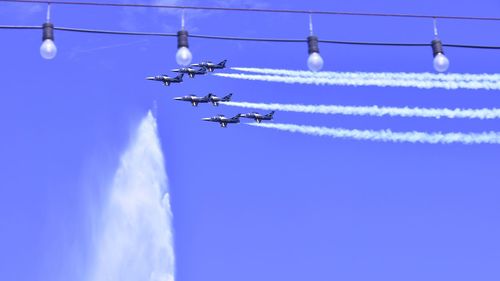Low angle view of airplane flying against blue sky
