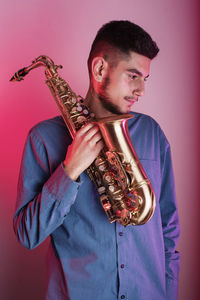 Young man playing guitar against gray background