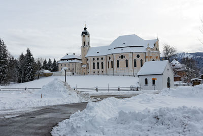 Empty road amidst snow covered field leading towards wies church at winter