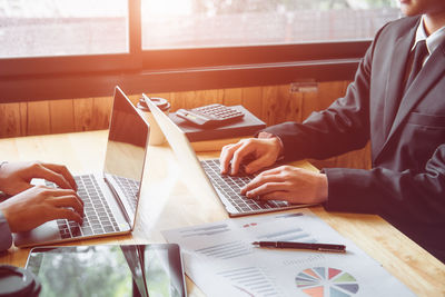 Midsection of man using laptop on table