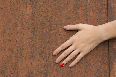 Cropped hand of woman touching rusty metal