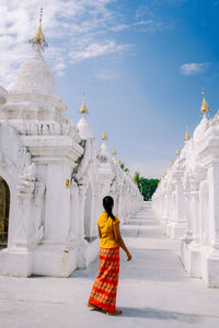 Rear view of woman walking in temple against sky