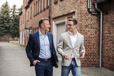 Two businessmen talking at brick building