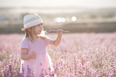 Cute girl smelling flower in field