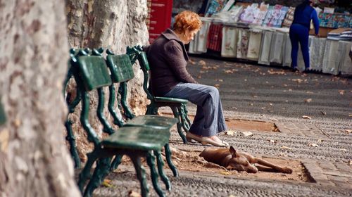 Side view of woman sitting on bench in park