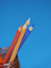 Low angle view of colored pencils against clear blue sky