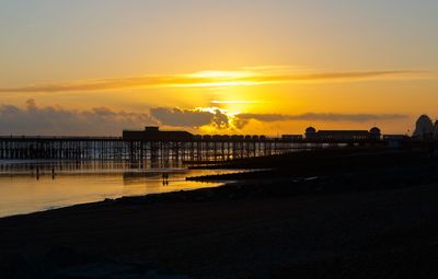 Silhouette pier on beach against sky during sunset