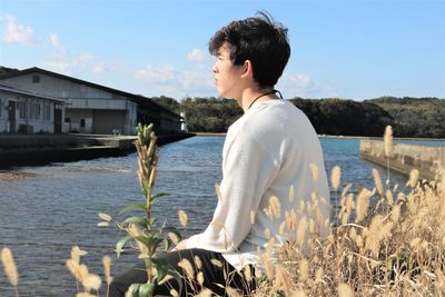 Side view of young woman standing by lake