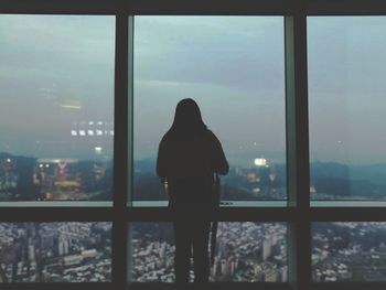 Rear view of woman looking through window