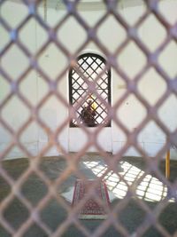 Full frame shot of metal grate window with girl in the window on opposite site.