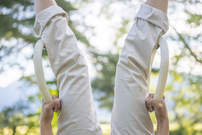 Midsection of woman hanging upside down on gymnastic rings