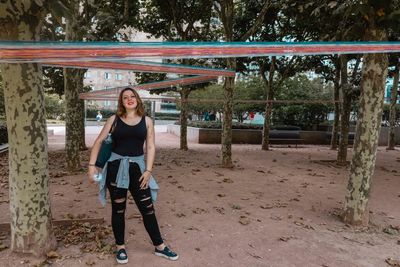 Portrait of young woman standing against trees