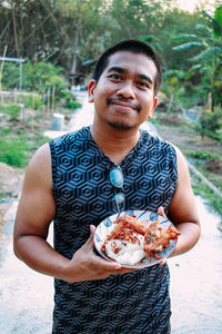 Portrait of smiling young man holding food