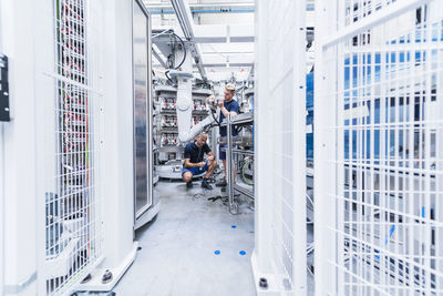 Two colleagues working at industrial robot in modern factory