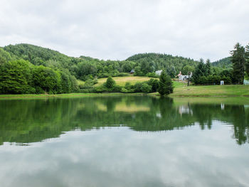 Scenic view of lake by trees against sky