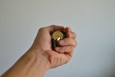 Close-up of hand holding ring over white background