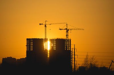 Low angle view of electricity pylon against sky during sunset